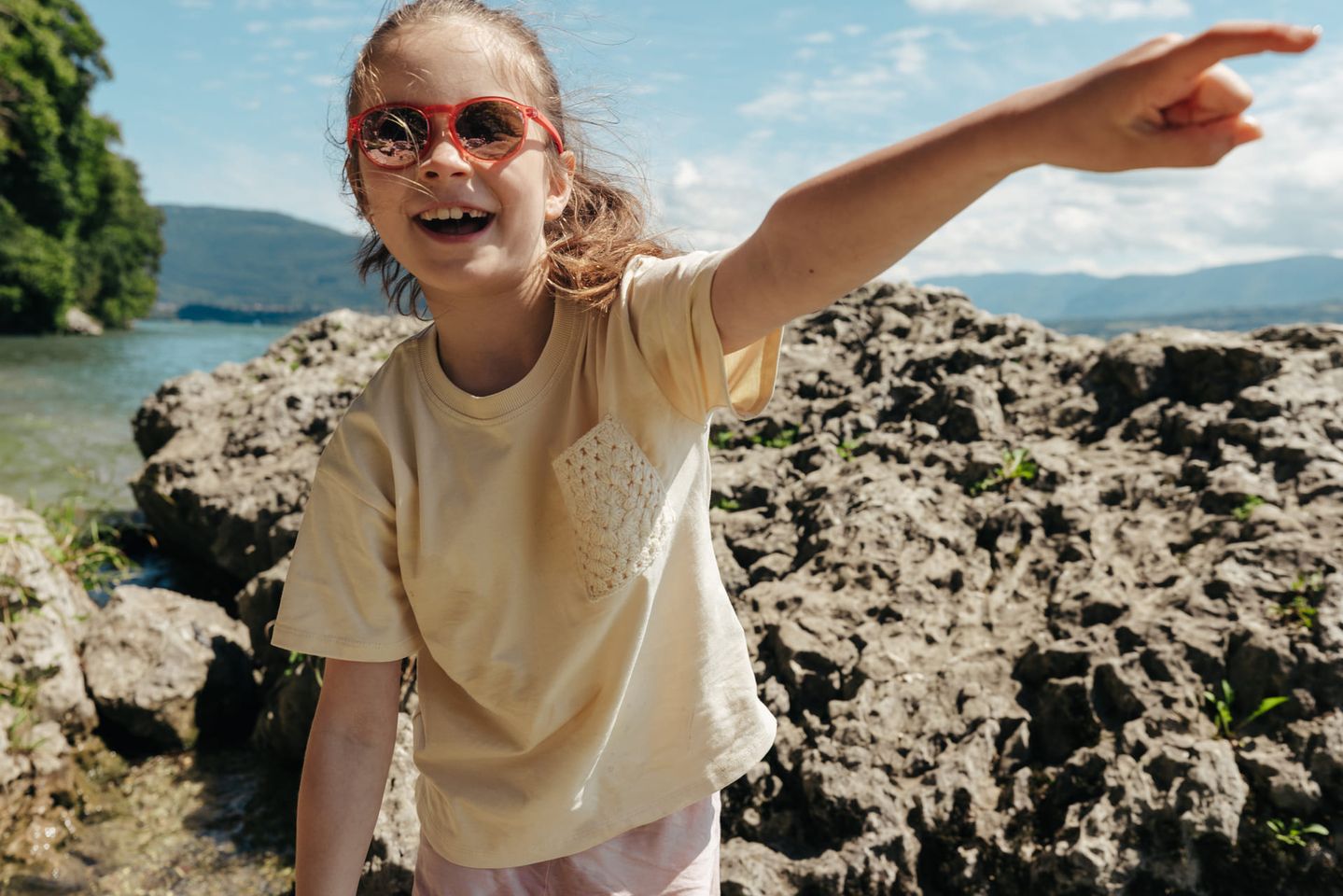 Ein junges Mädchen mit Sonnenbrille zeigt mit ihrem Finger auf etwas