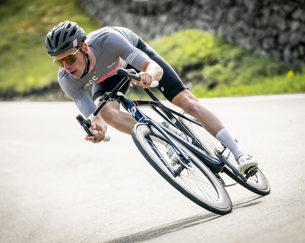 Ein Mann mit Brille fährt mit dem Fahrrad auf einer Straße