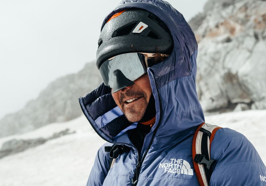 Ein Mann in einer blauen Jacke und Skibrille steht auf einem Berg