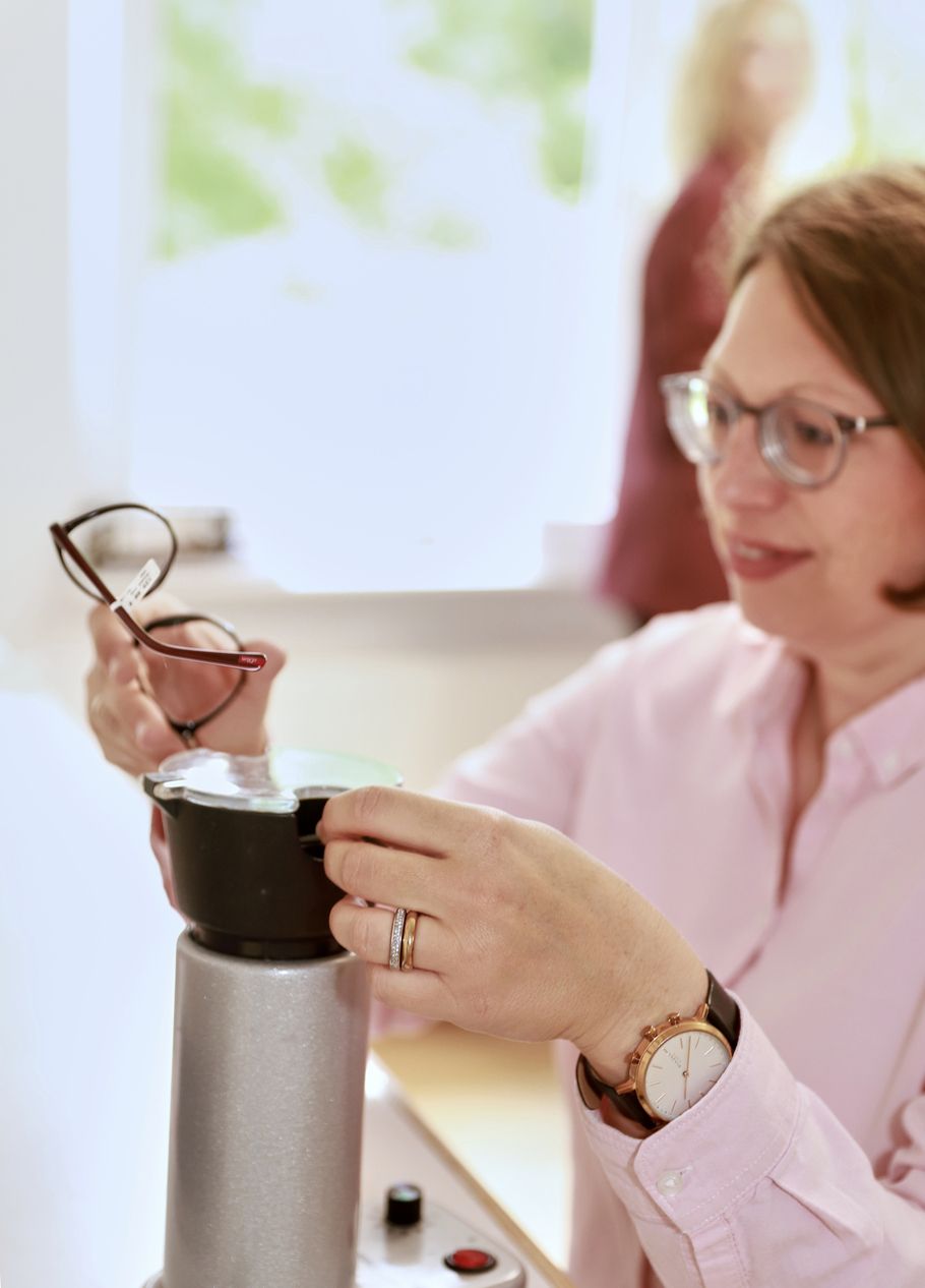 Optikerin prüft eine neue Brillenfassung auf Qualität und Passform